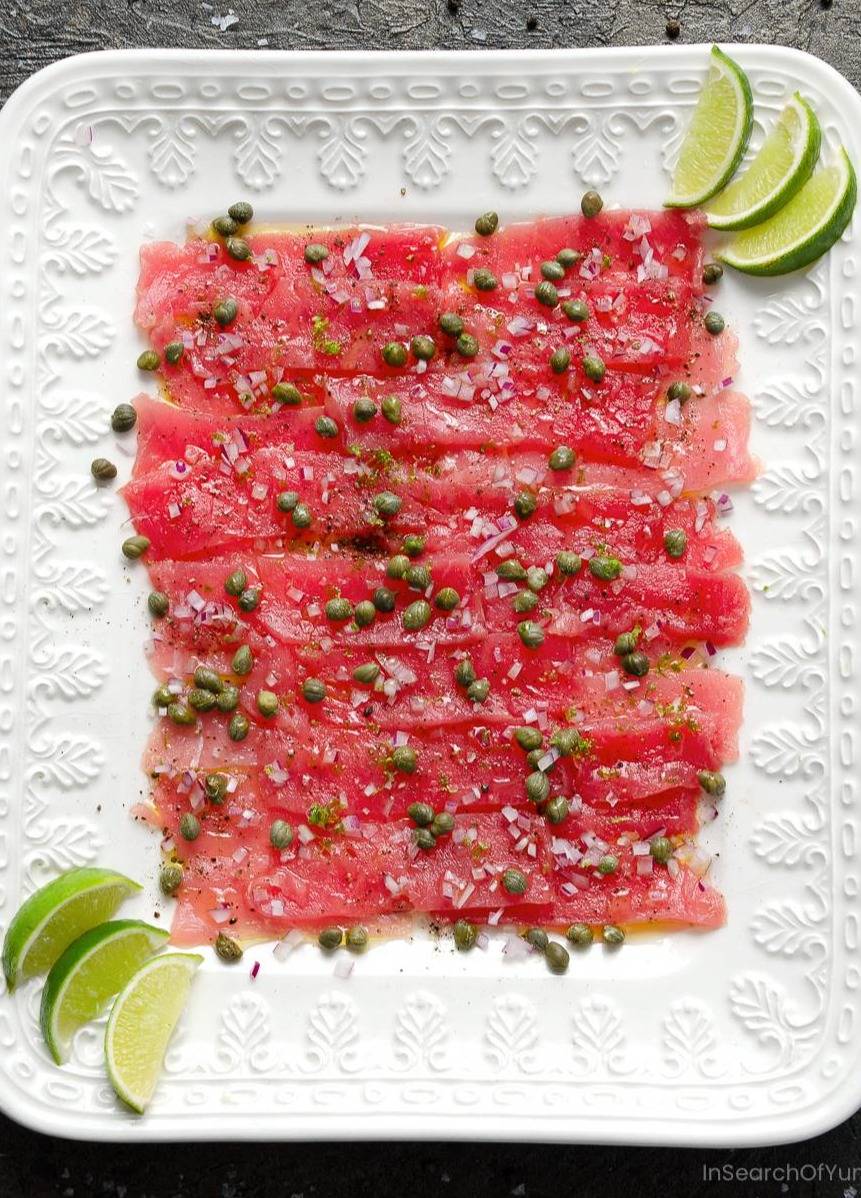 Tuna carpaccio on a white platter.