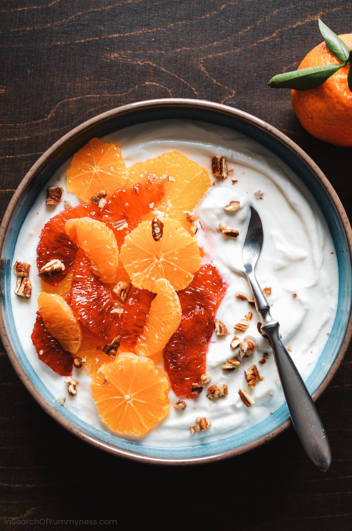 A bowl of Greek yogurt topped with supremes of citrus and toasted nuts.