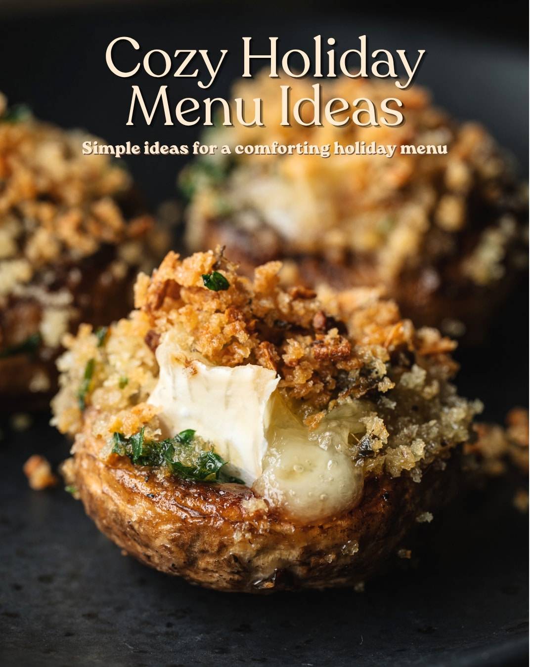A brie-stuffed mushroom with melting cheese on a black slate serving board. Text overlay says "Cozy Holiday Menu Ideas".
