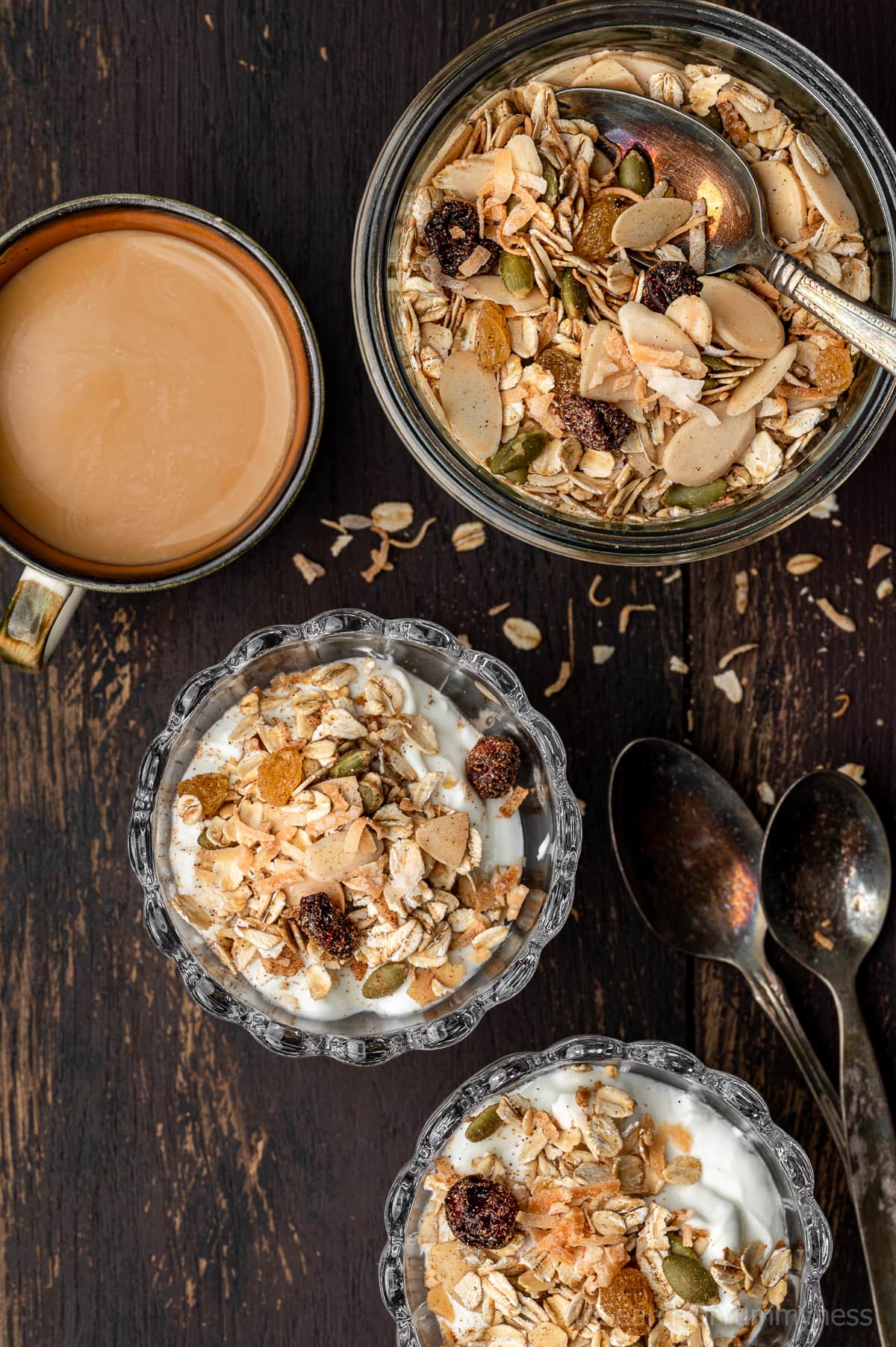 Two muesli yogurt parfaits on a table next to a Weck jar of more toasted muesli.