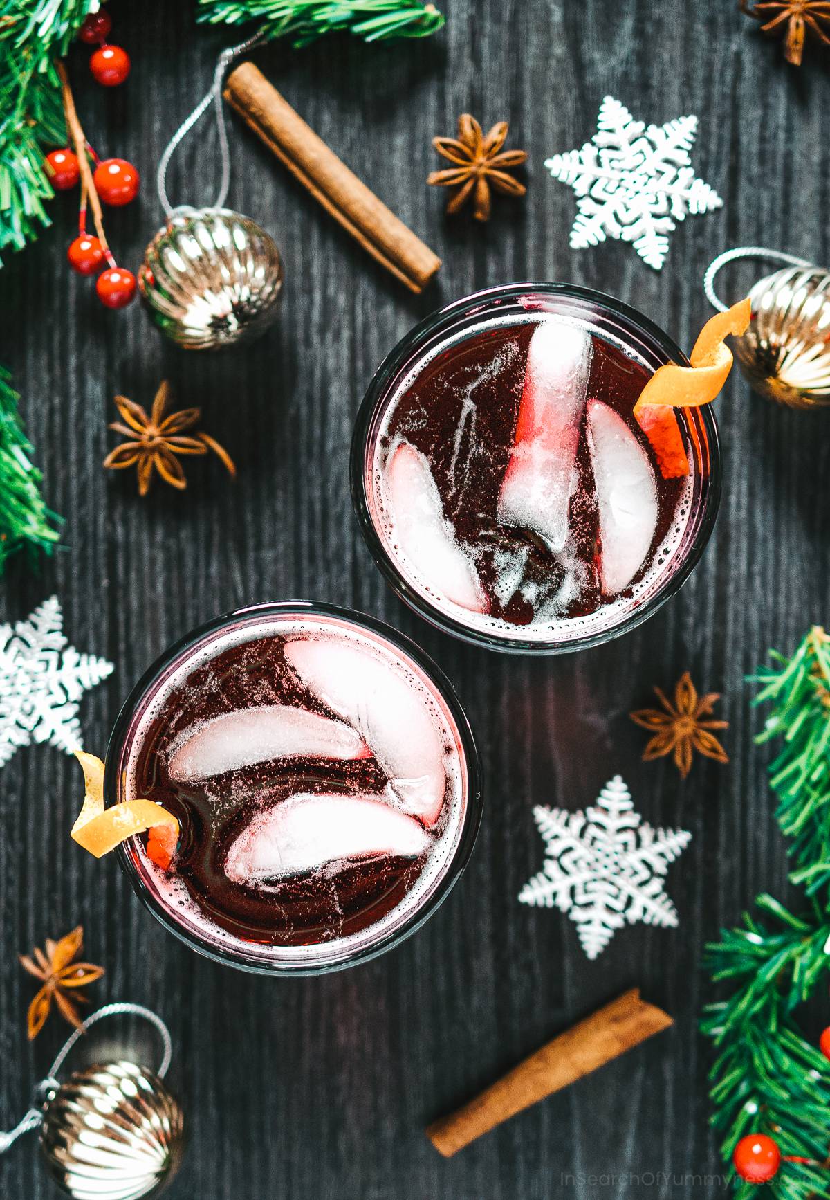 Two glasses of sorrel drink with ice cubes next to Christmas decorations.