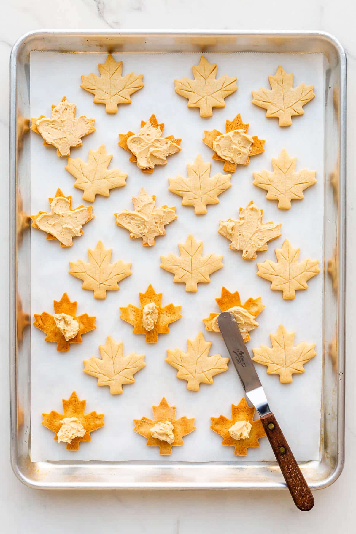 Several maple cream cookies on a sheet pan lined with parchment paper.