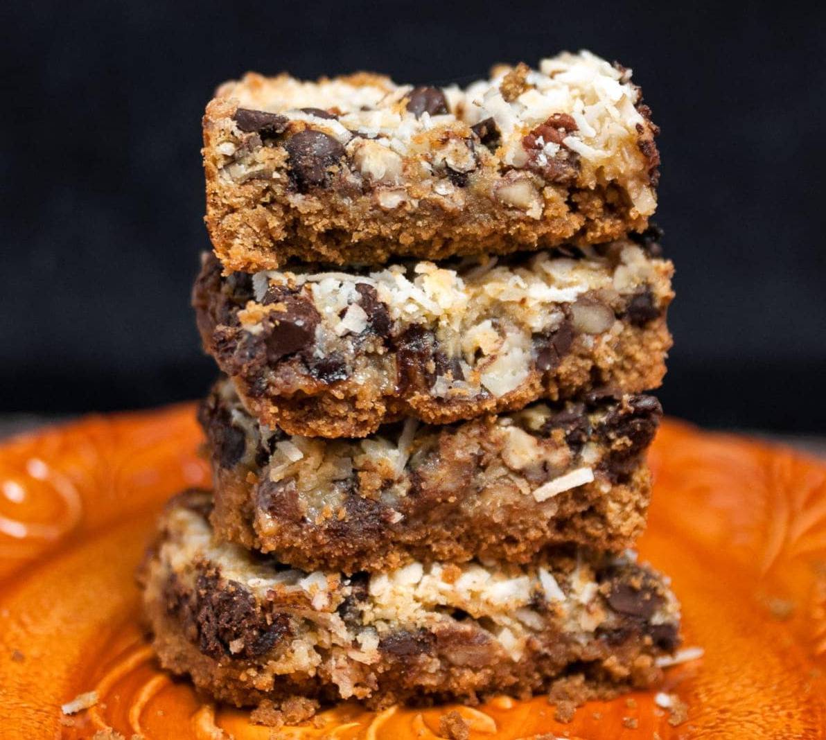 a stack of pumpkin cookie bars with coconut, chocolate chips and pecans