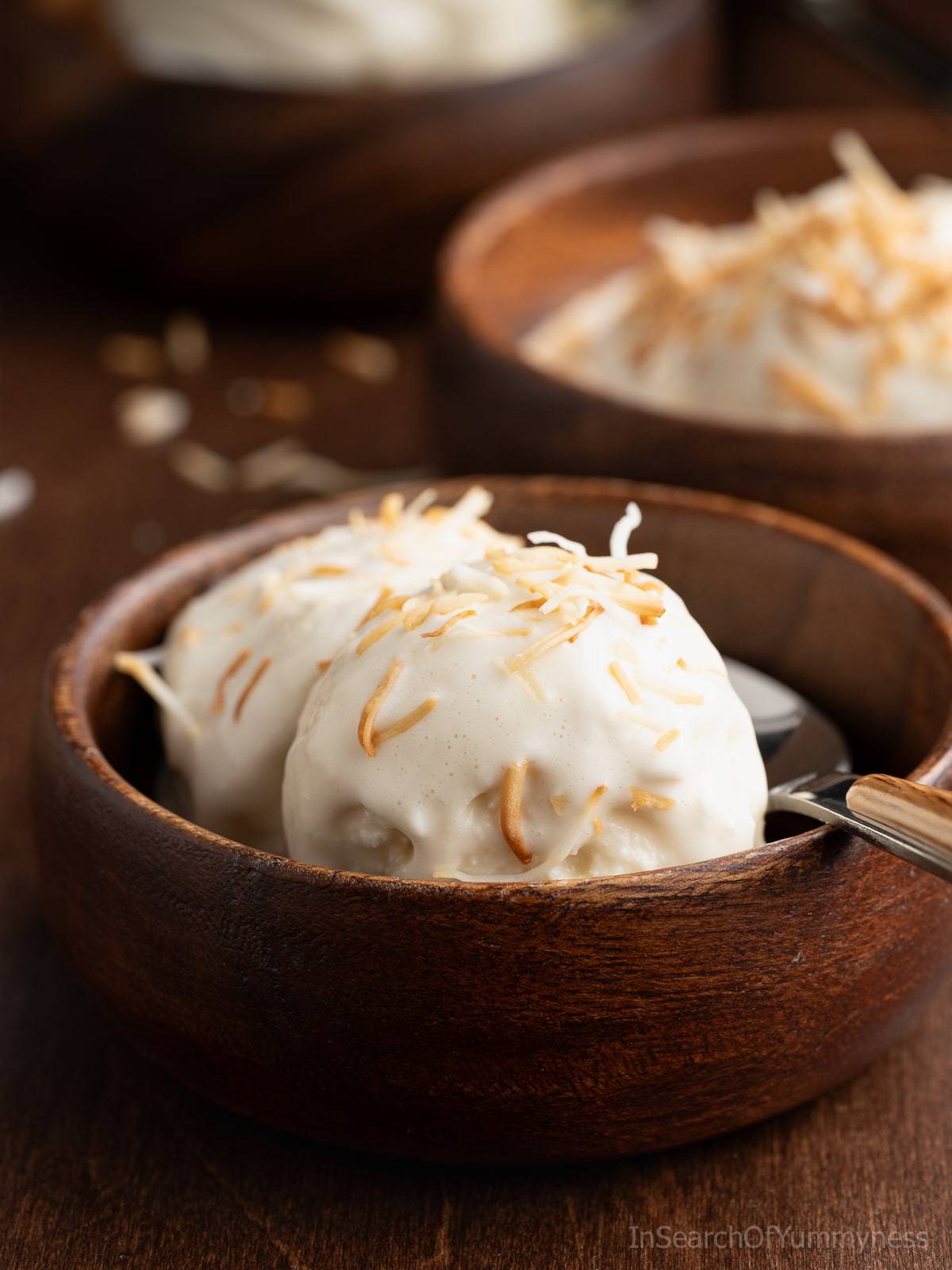 A wooden bowl with two scoops of coconut ice cream
