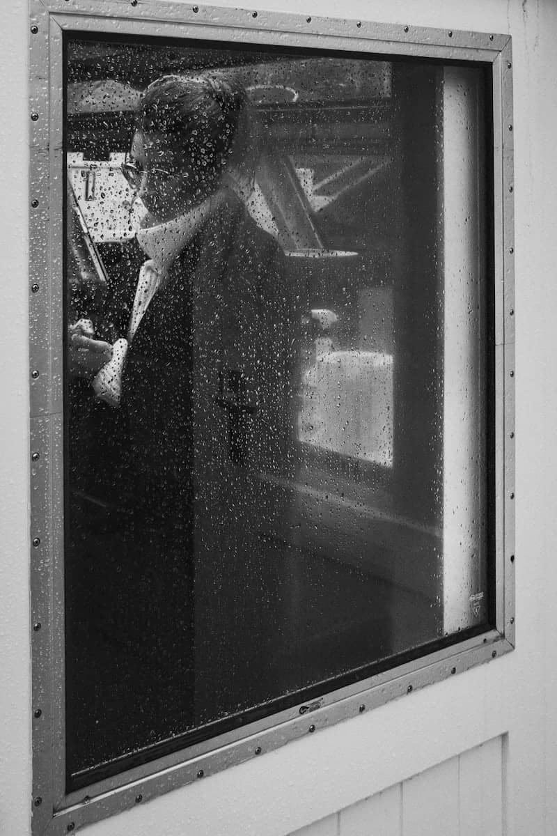 A person is viewed through a rainy window.