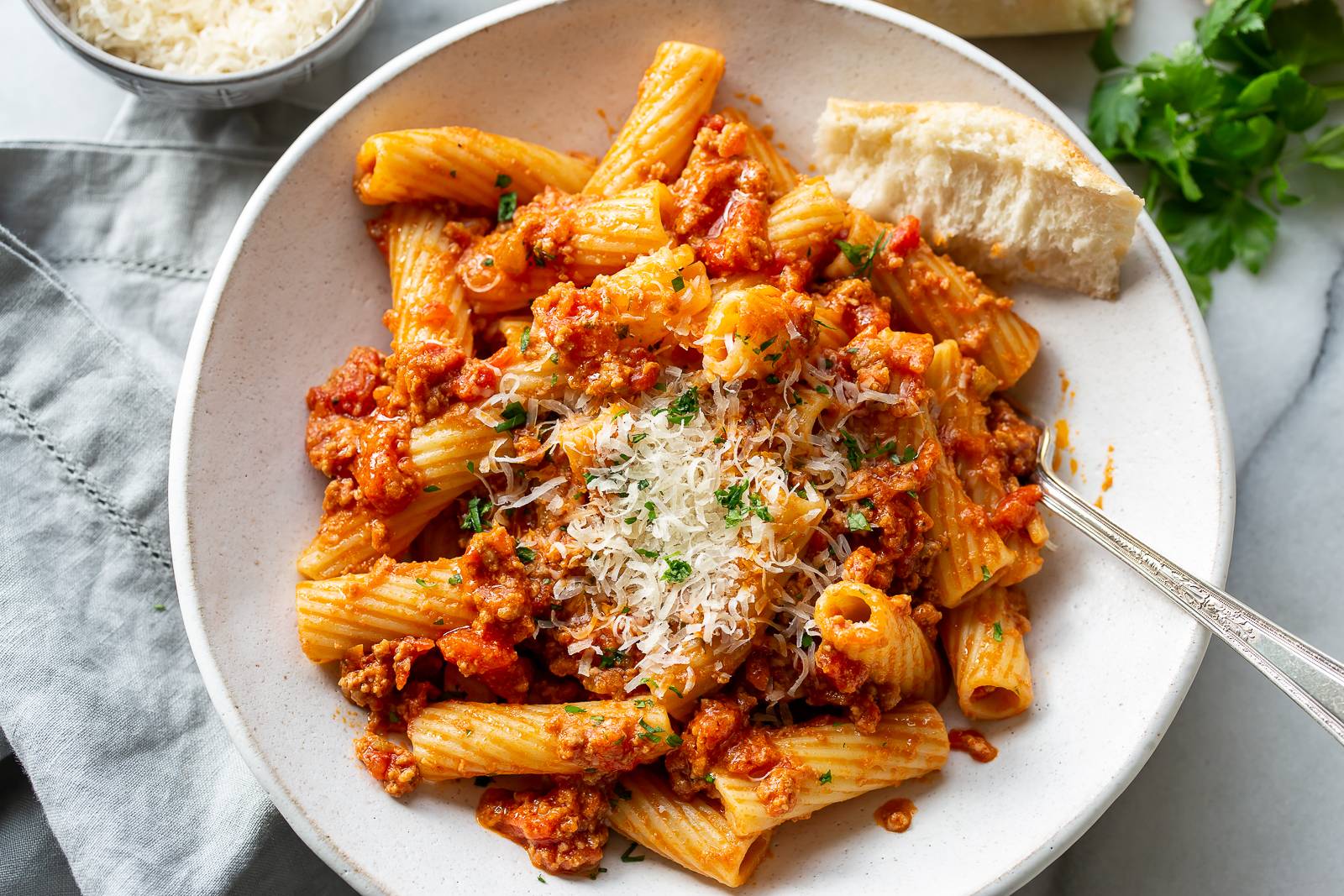 Rigatoni Bolognese in a bowl with Parmesan and parsley