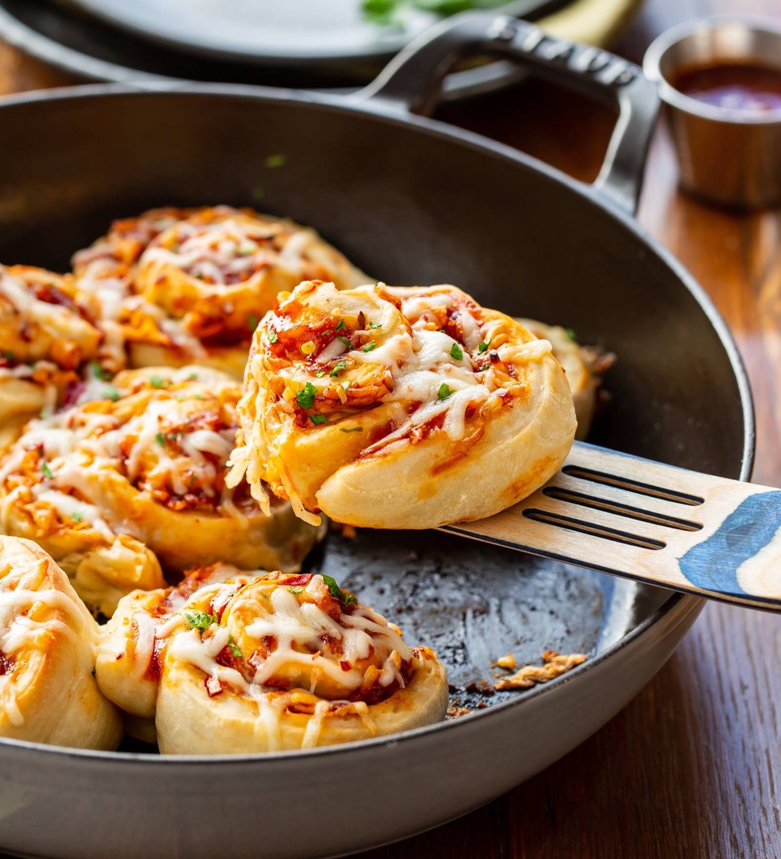 A pan of pizza rolls with one on a spatula