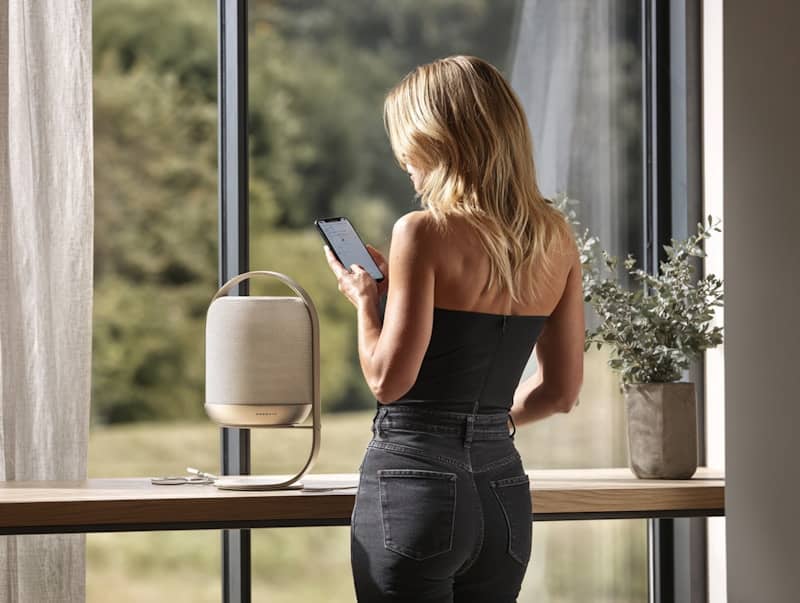 Woman using smartphone by a speaker near a window.