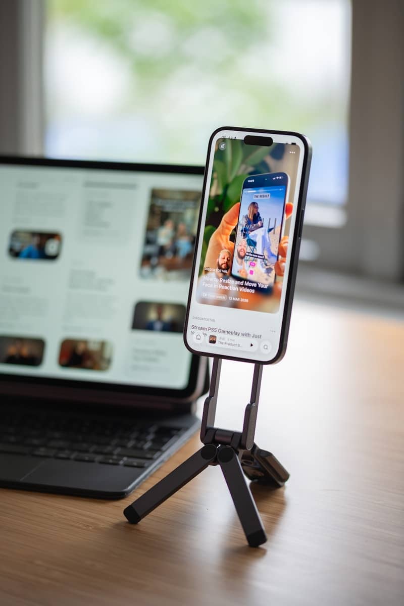 Smartphone on tripod displaying social media next to a laptop.
