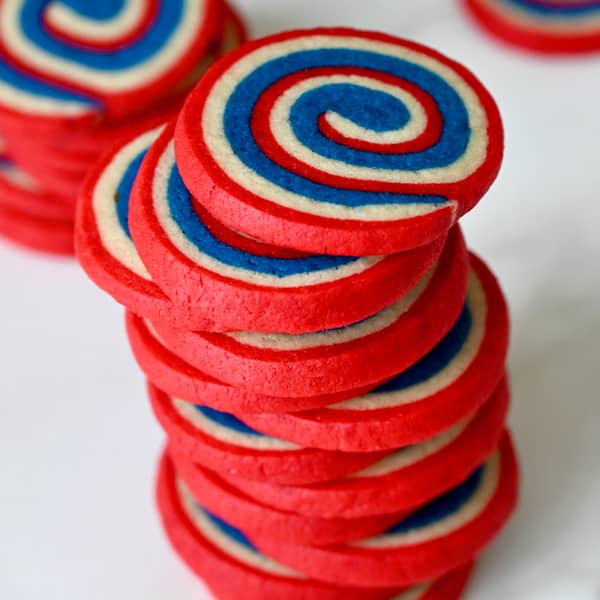 Red, white and blue pinwheel cookies stacked high.