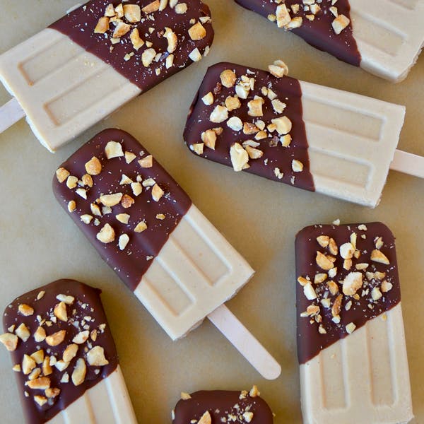 Peanut butter frozen yogurt pops dipped in chocolate and garnished with chopped peanuts.