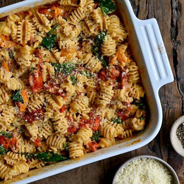 Baked Boursin Cheese Pasta with Sundried Tomatoes and Spinach in a white baking dish.