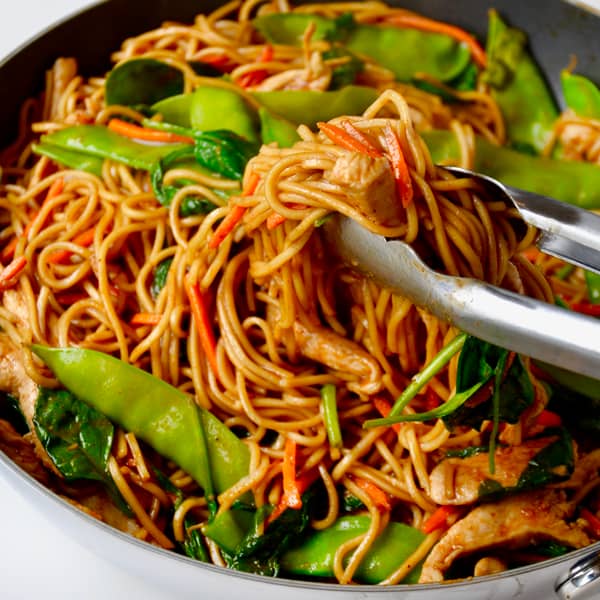 A large skillet containing lo mein with veggies.