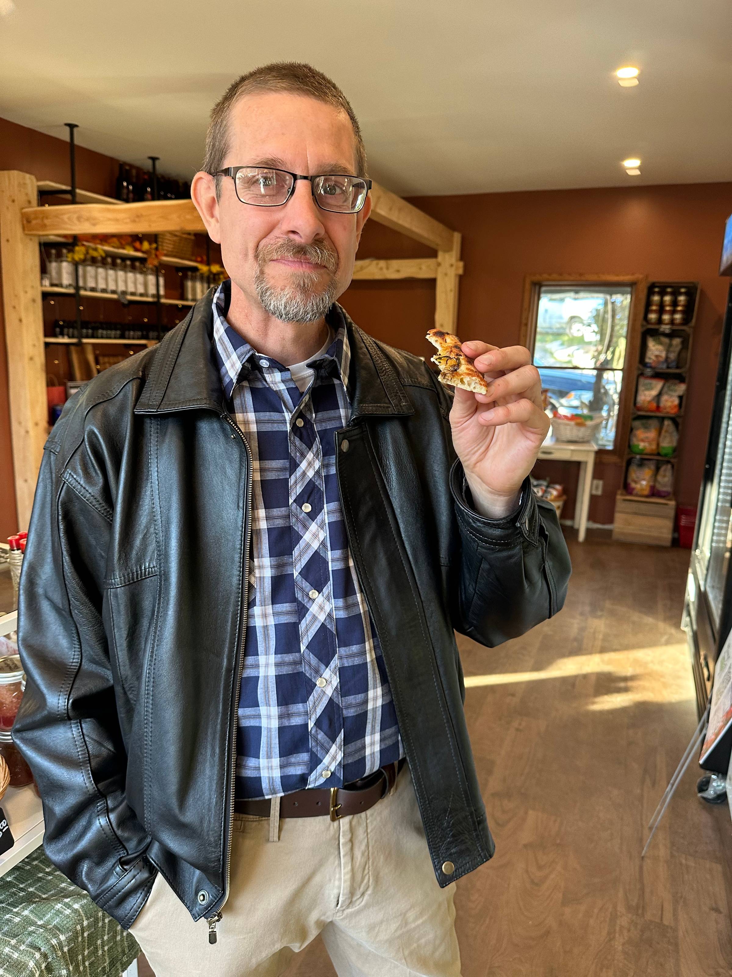 Reuben enjoying a taste of a homestead specialty pizza in the cozy farm store and barn beam bar