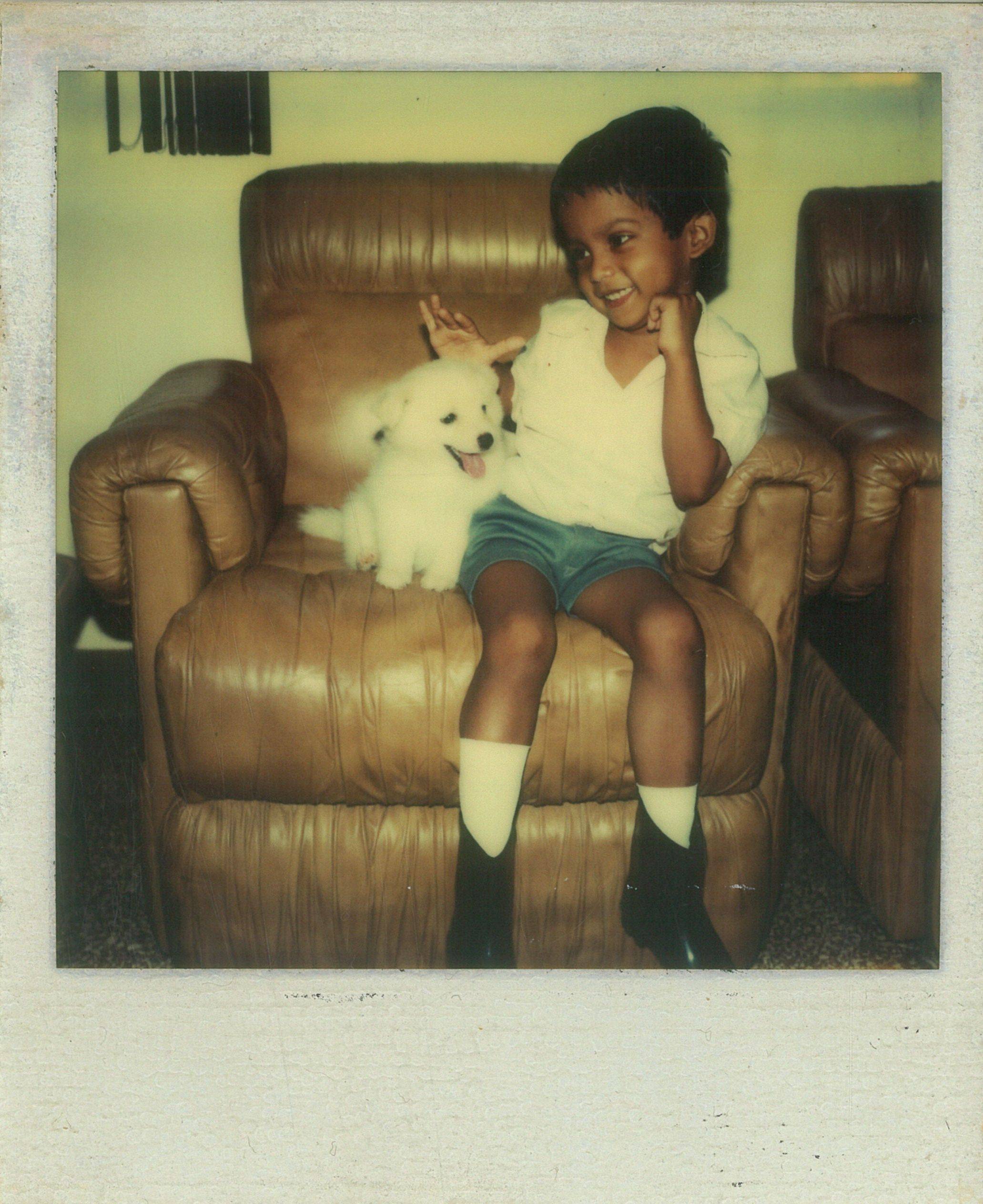 Baby Nik with puppy on chair smiling