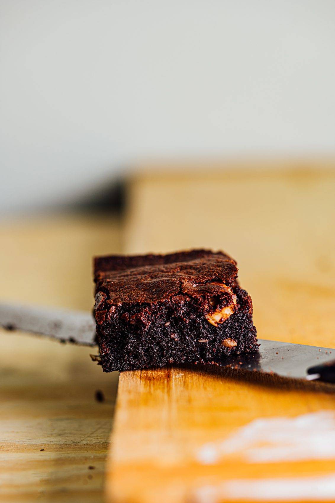 Chocolate Hazelnut Brownie sitting on a knife on a cutting board.