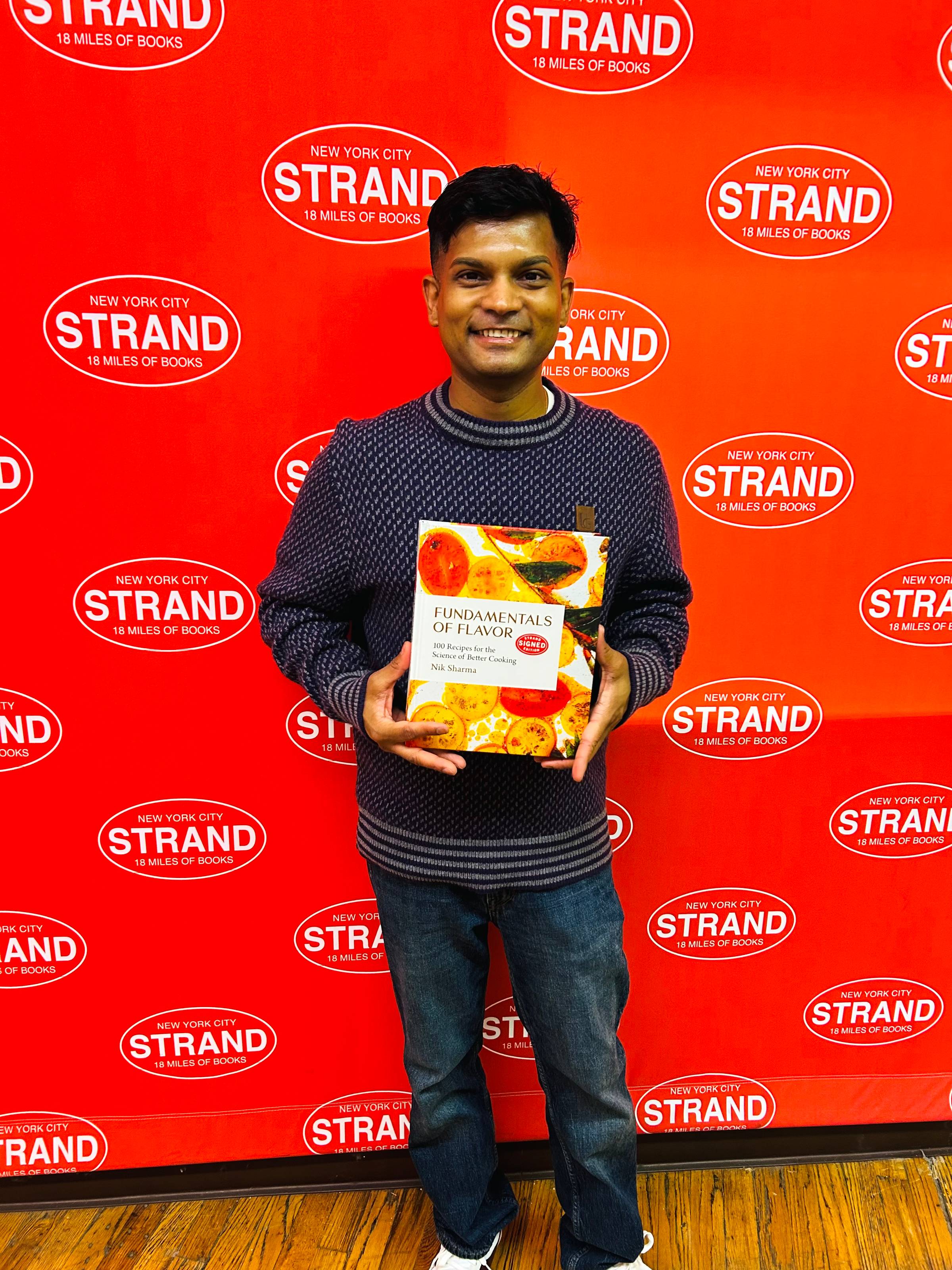 Nik holding a copy of Fundamentals of Flavor at Strand Book Store