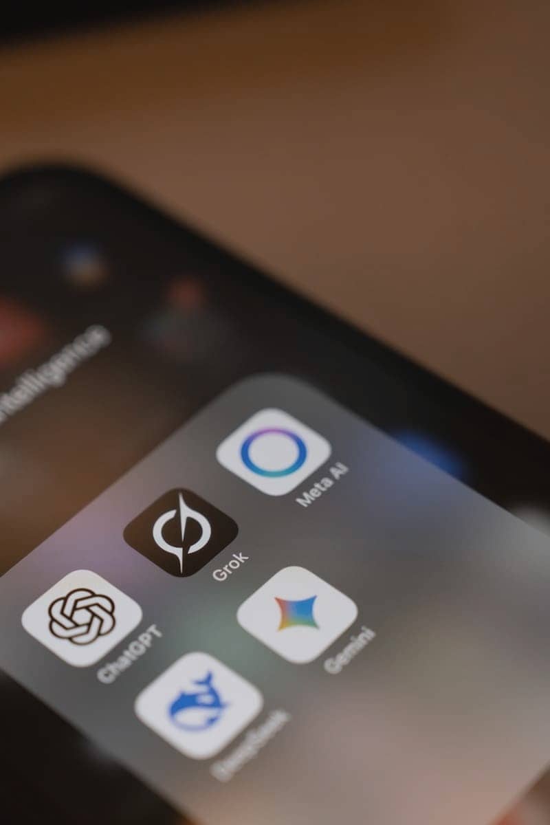 Smartphone screen displays ai app icons: chatgpt, grok, meta ai, gemini.