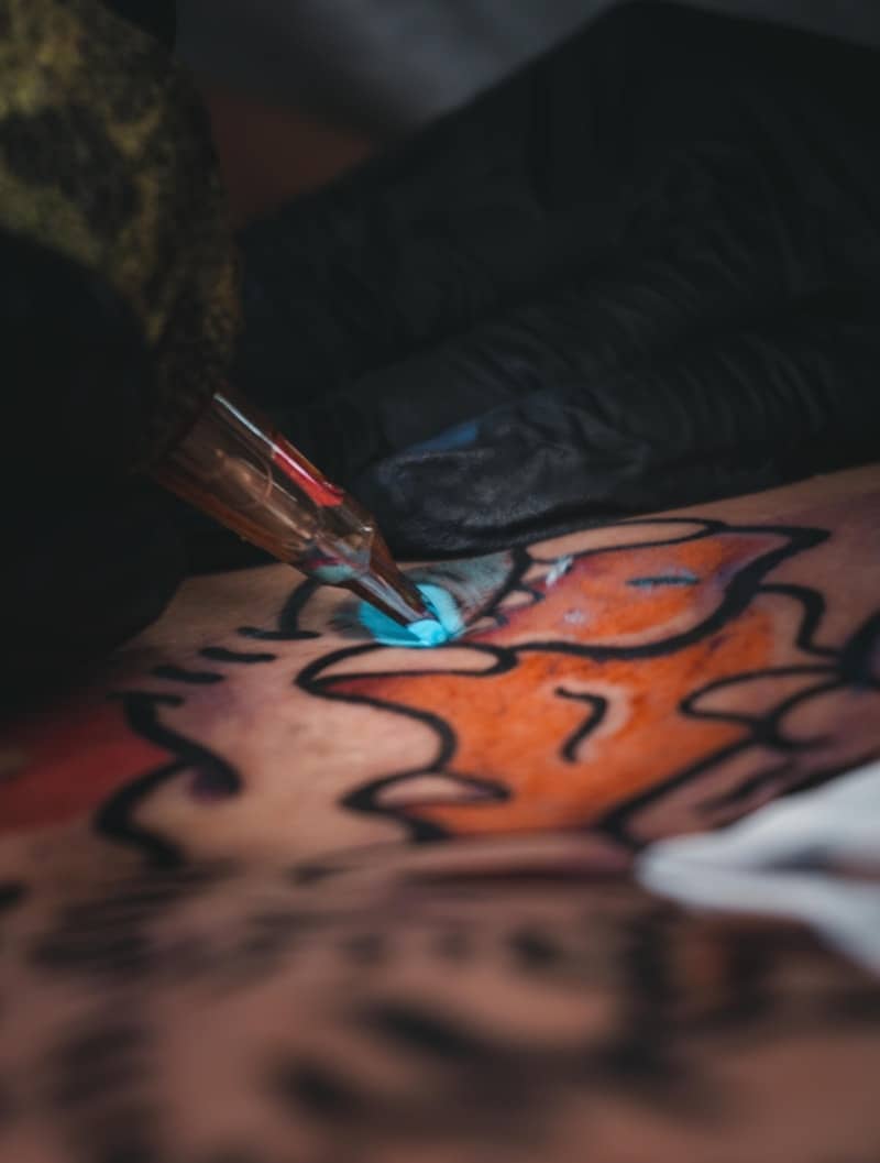 A tattoo artist is inking a design.