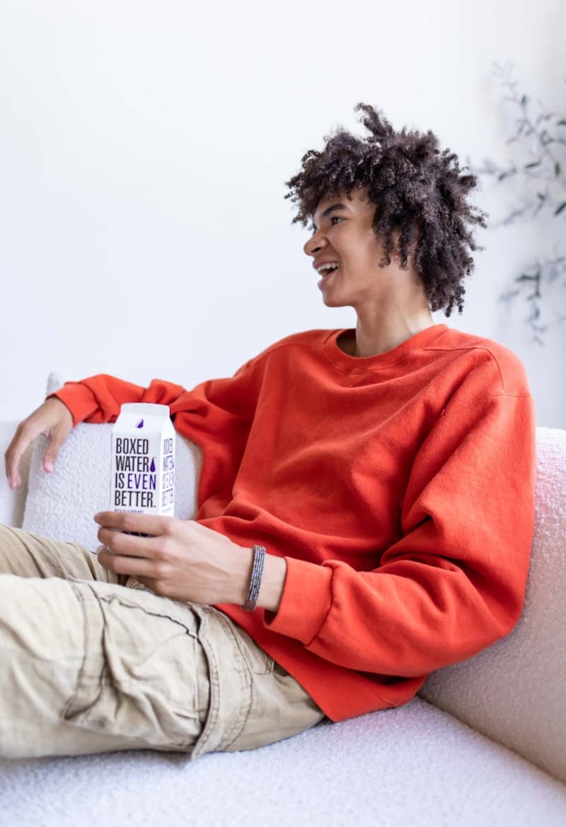 a person siting on a white couch holding a container of water
