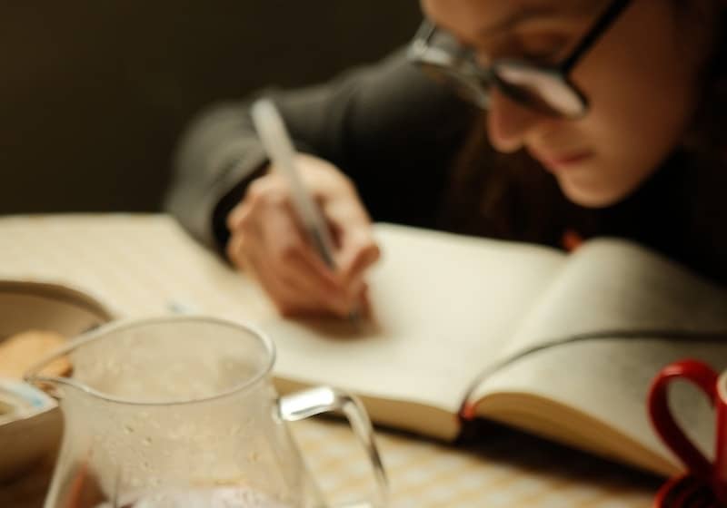 A woman sitting at a table with a laptop and a cup of coffee