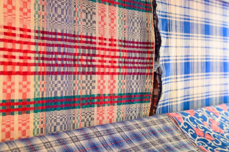 A bed with plaid sheets and pillows on top of it
