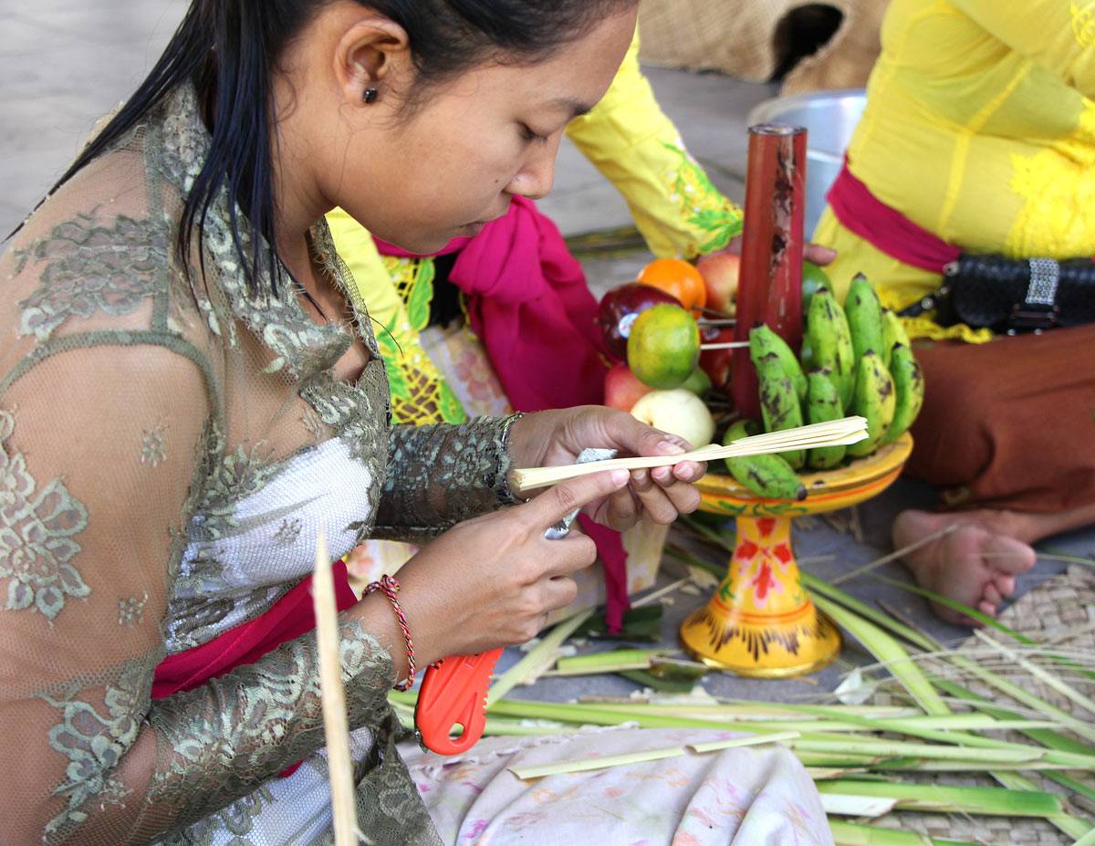A young Balinese woman makes palm leaf offerings
