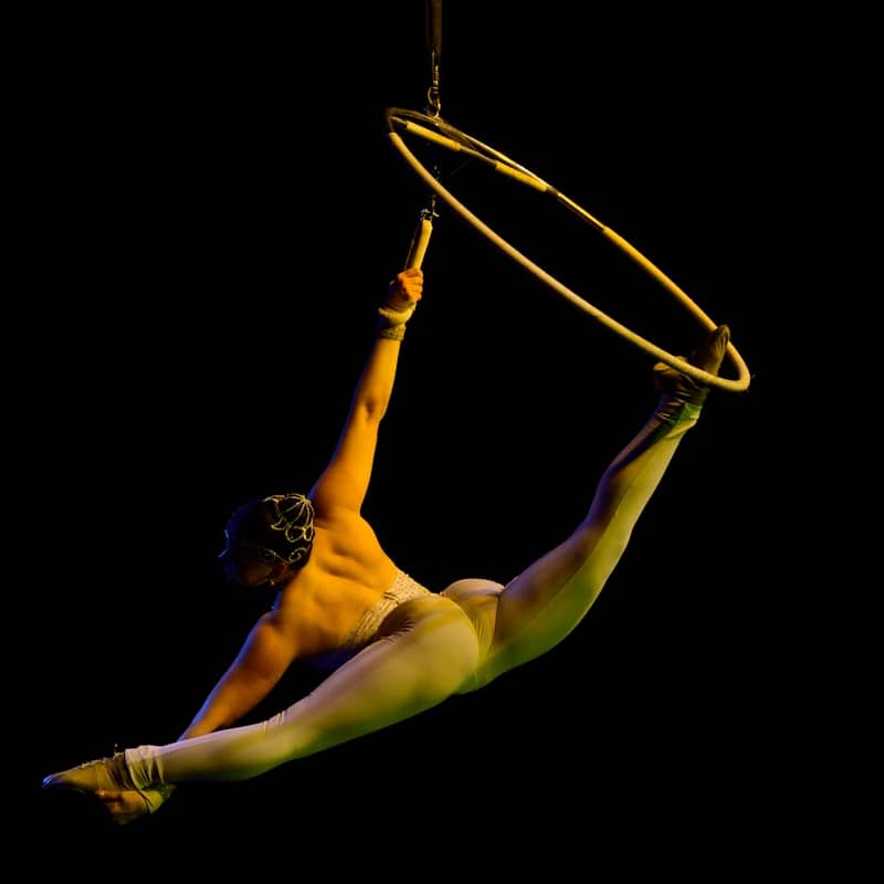 A shirtless man hanging upside down on a hoop