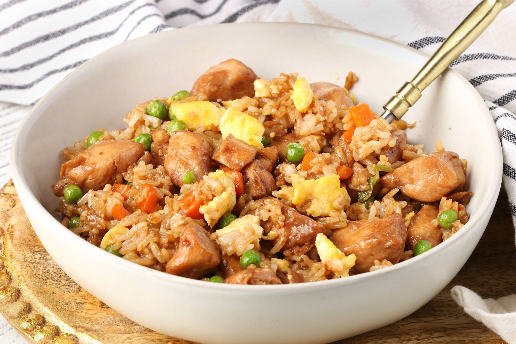 Chicken Fried Rice in a white bowl on a wood platter.