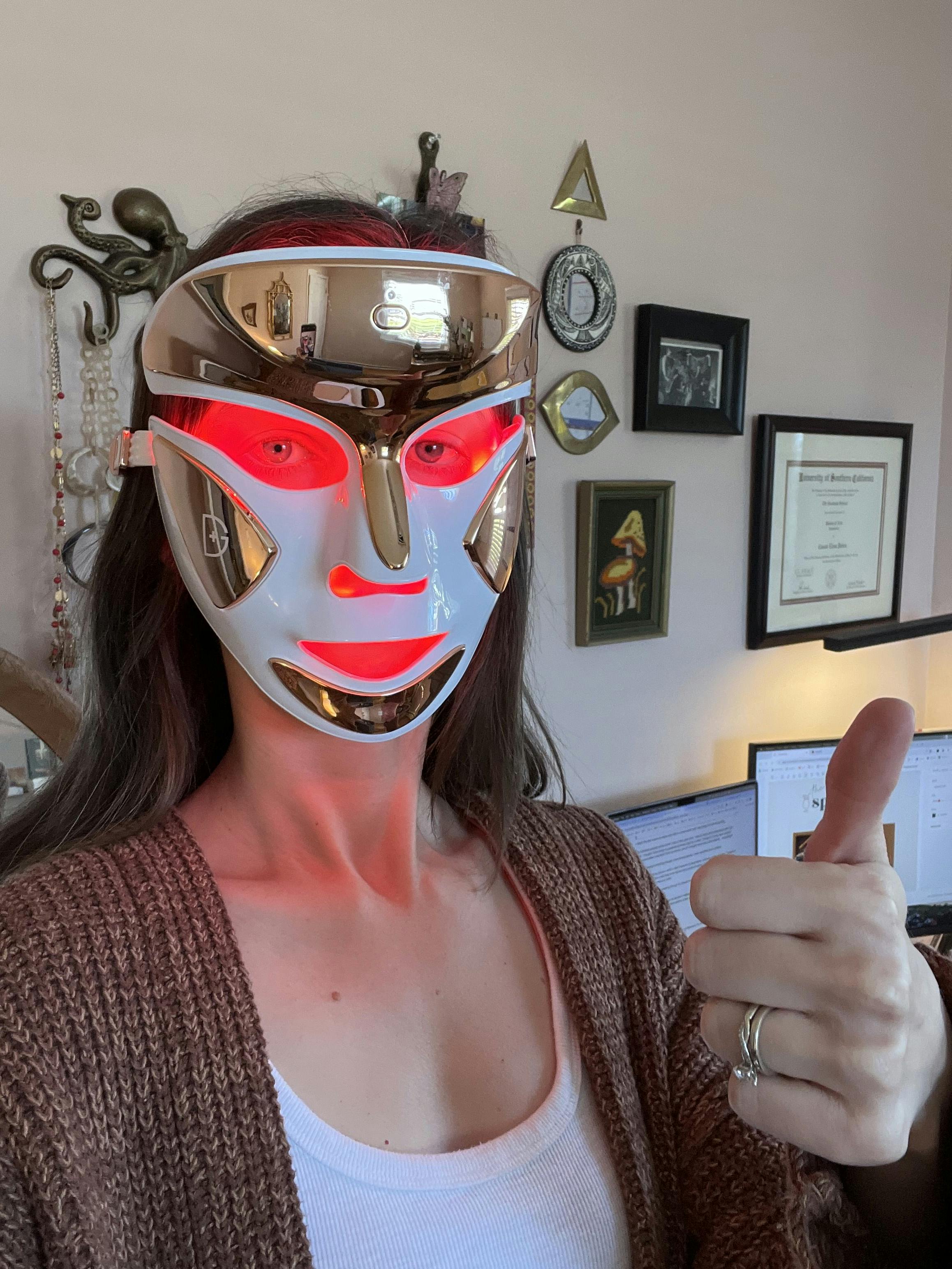 photo of Cassie wearing an illuminated LED mask, giving the thumbs-up