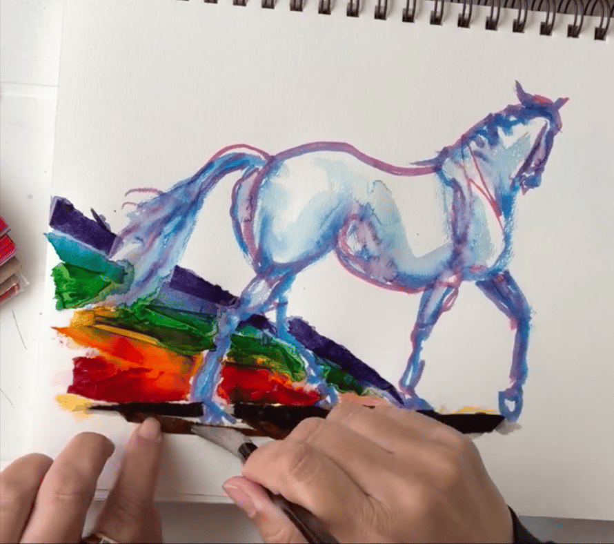 Photo of artist's hands applying water to tissue paper on an art piece with a trotting horse leaving a rainbow wake.