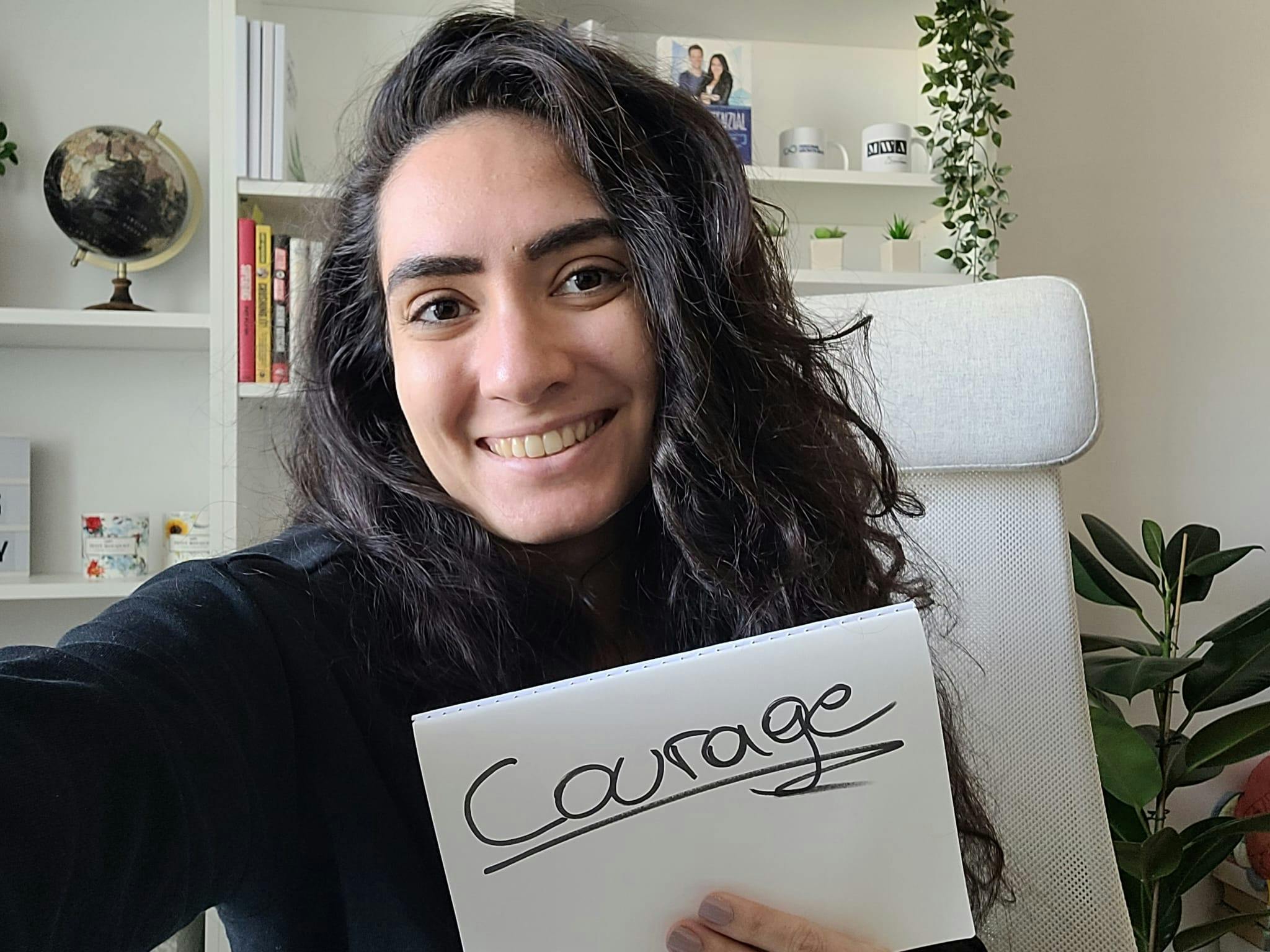 Sinem holding a sign that says "Courage"