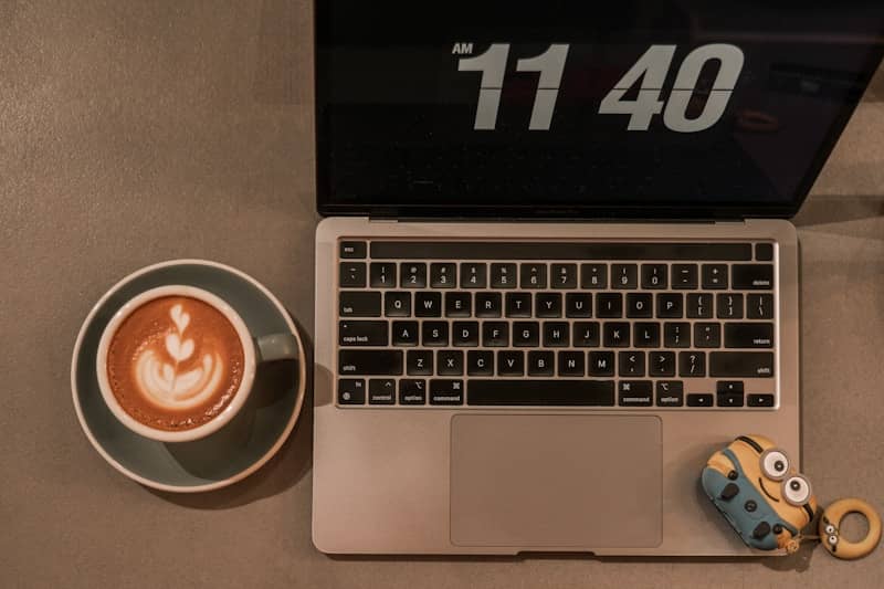 Coffee and a laptop on a table at eleven forty.
