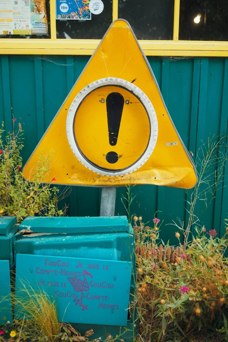 Yellow warning sign with exclamation mark outdoors.
