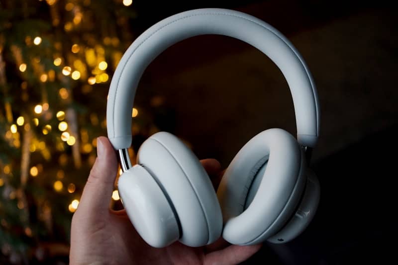 Light blue headphones held in a hand with bokeh lights.