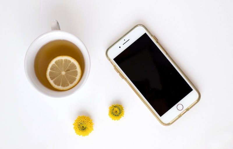 gold iPhone 8 plus near tea with sliced lemon