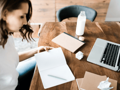 Woman sitting at a desk with laptop, notebook, and crumpled paper, representing quiet business strategy and messy middle for introverted entrepreneurs.