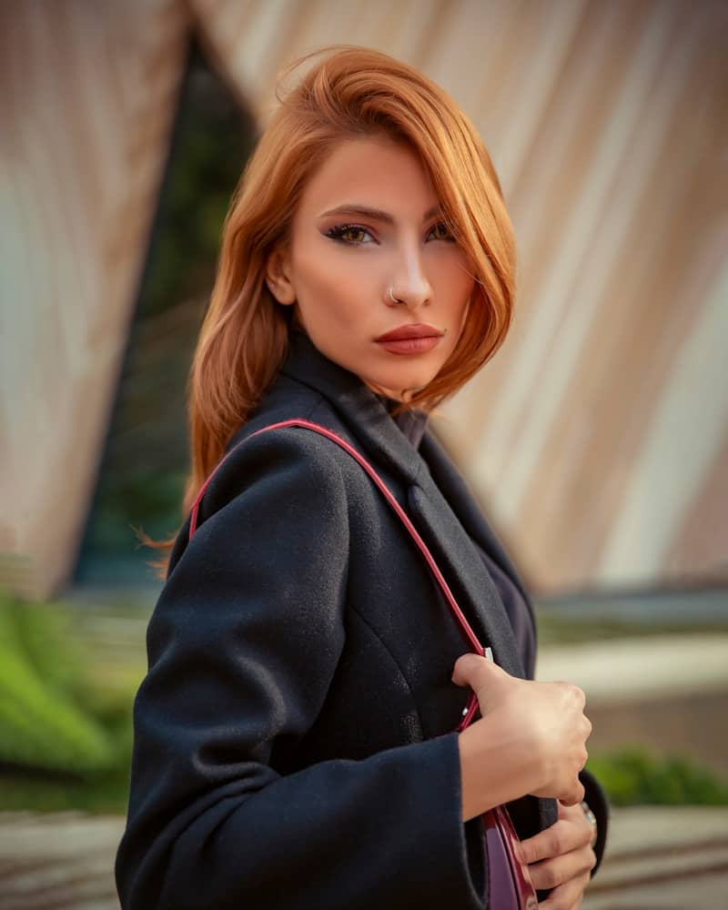 A woman with red hair is holding a purse