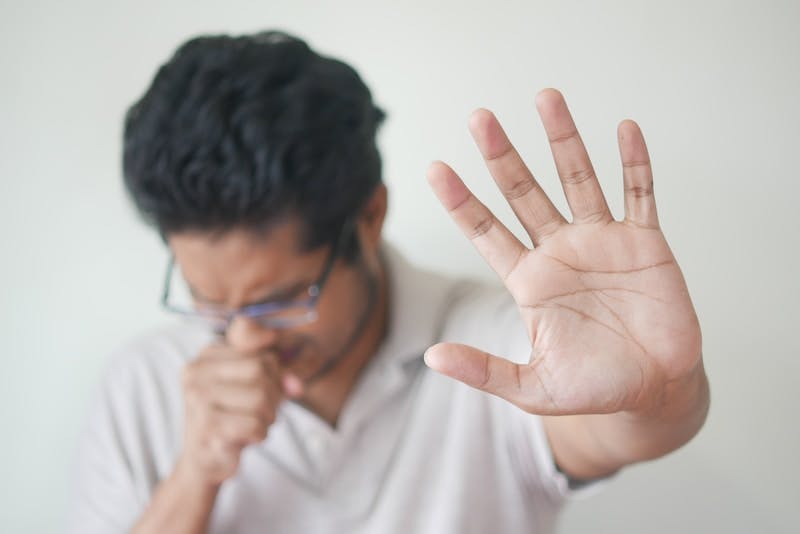 A man coughing with his hand up in front