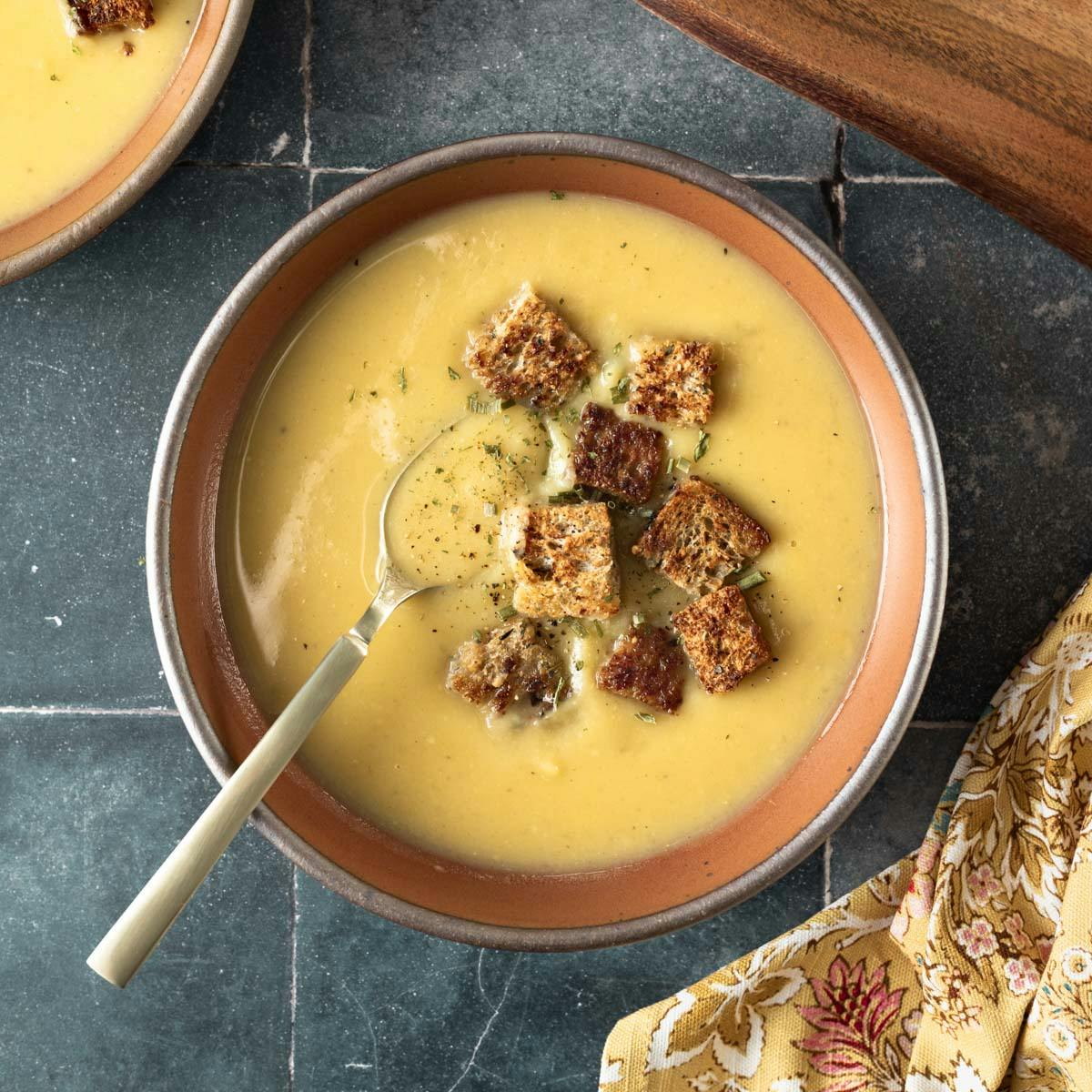 A rust-colored bowl filled with creamy soup topped with croutons.