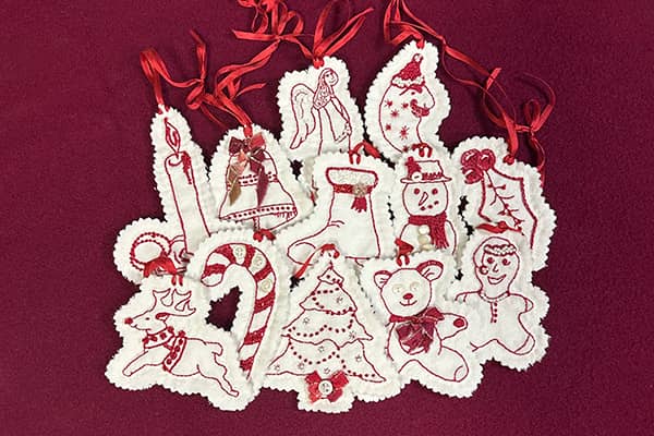 Redwork embroidered holiday ornaments, a full dozen shown here on a red background.