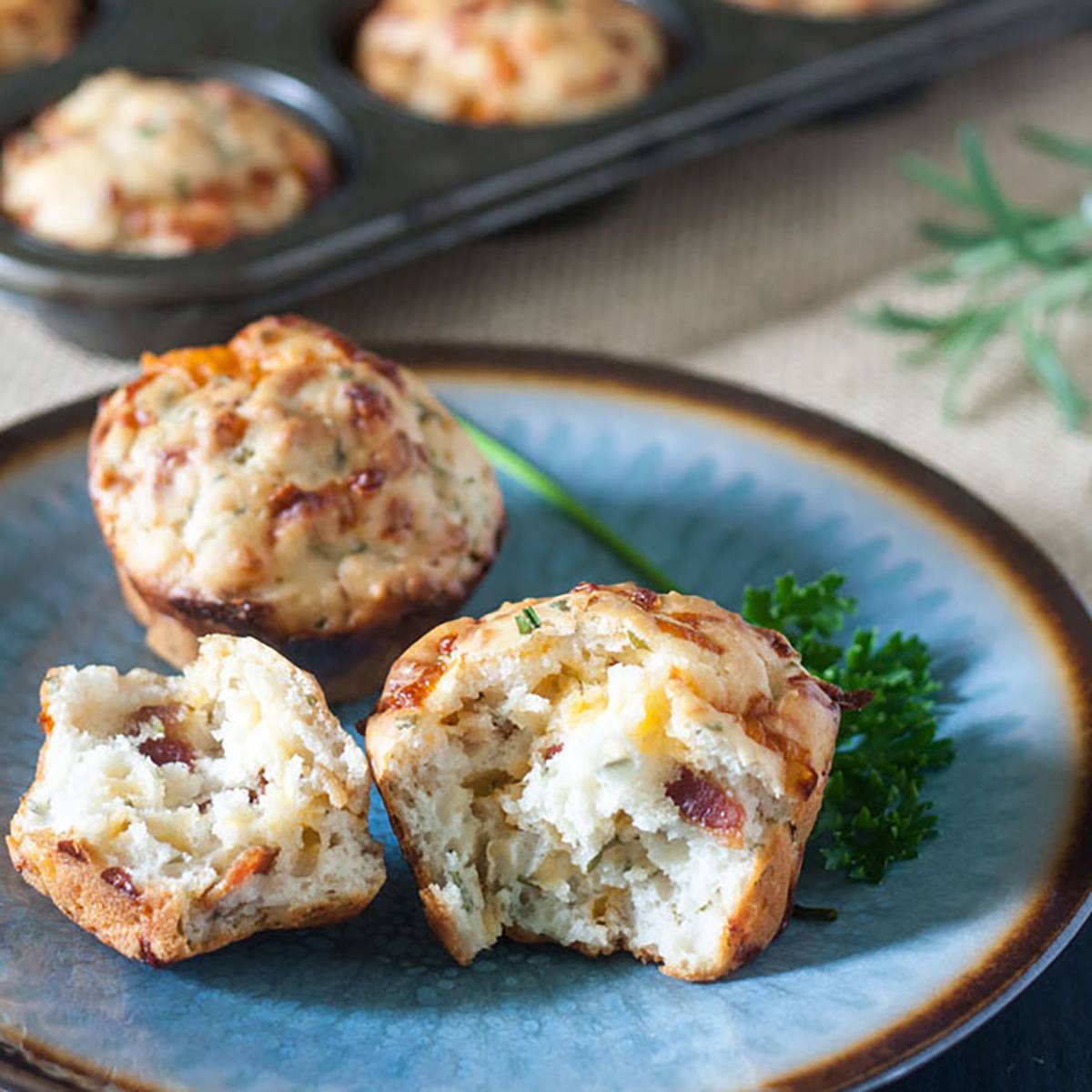 Picture of a cheese muffin broken in half on a blue plate.