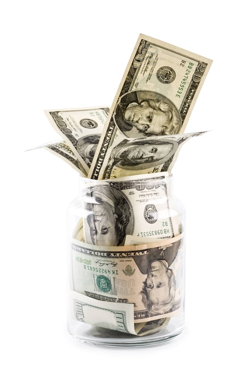 A glass jar filled with money sitting on top of a table