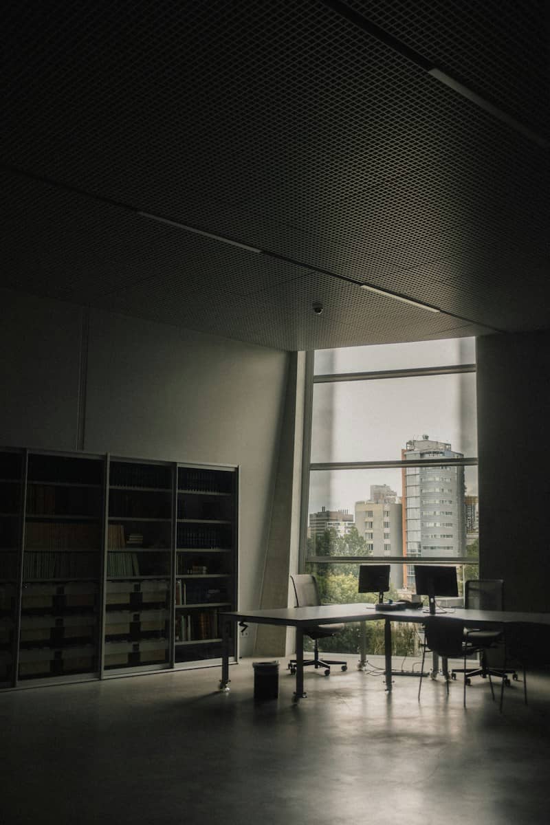 A modern office workspace with desks and computers overlooking a city skyline
