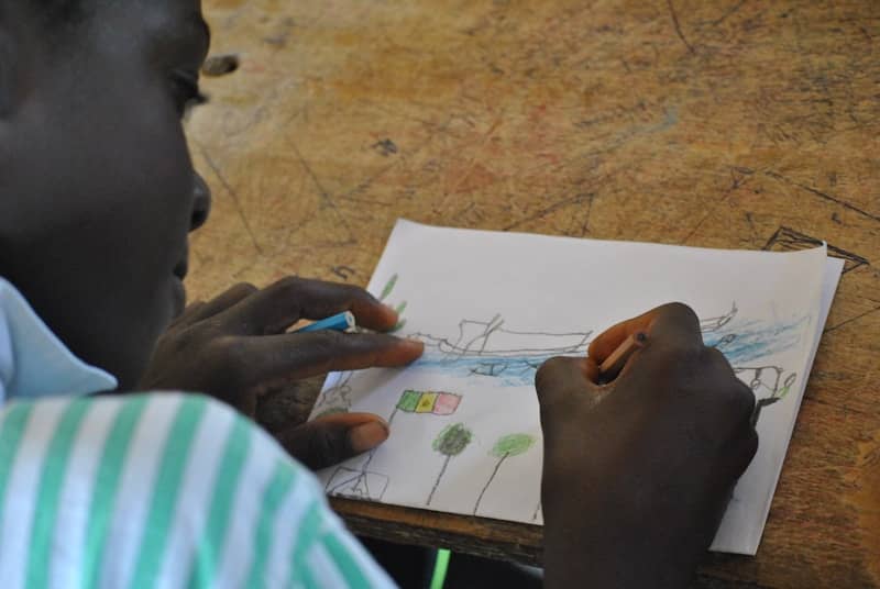 A child draws a picture with crayons.