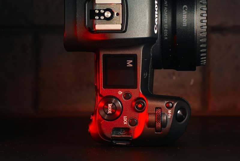 A Canon camera body with a lens adapter under dramatic red lighting