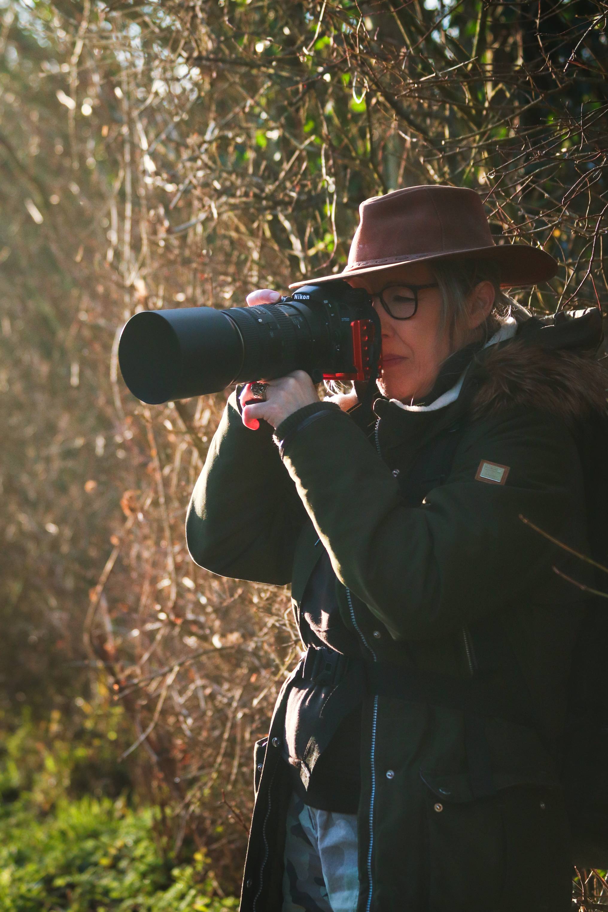 An image of a woman wearing a hat holding a camera in the autumn sun
