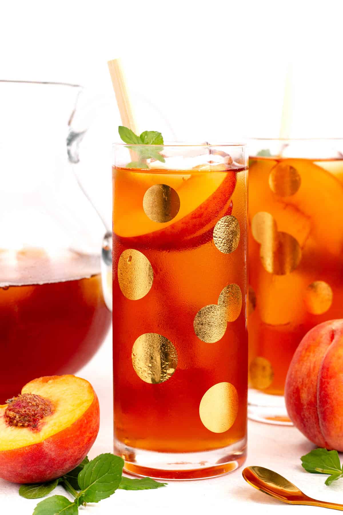 Two glasses of iced tea with slices of peach floating inside.