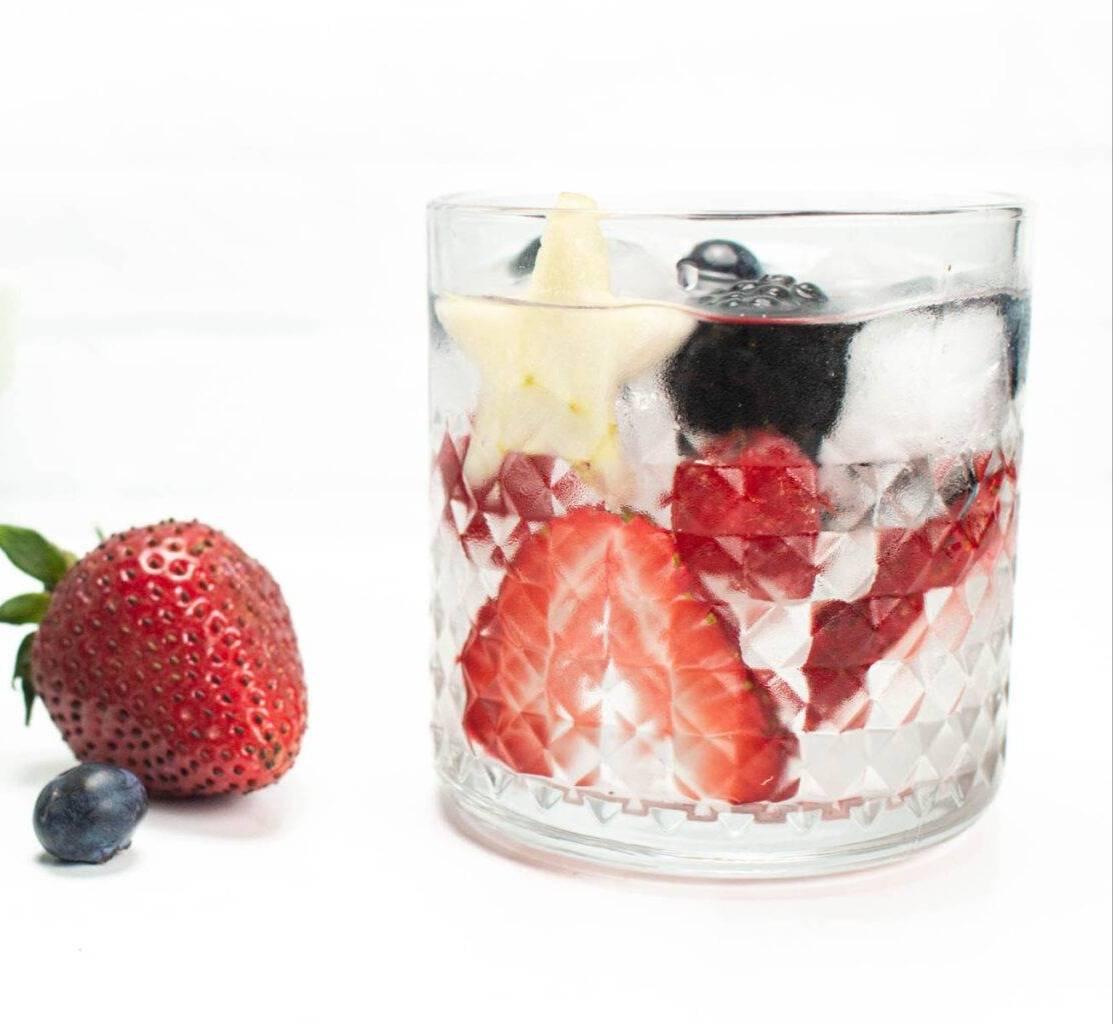A glass of ice water with berries.