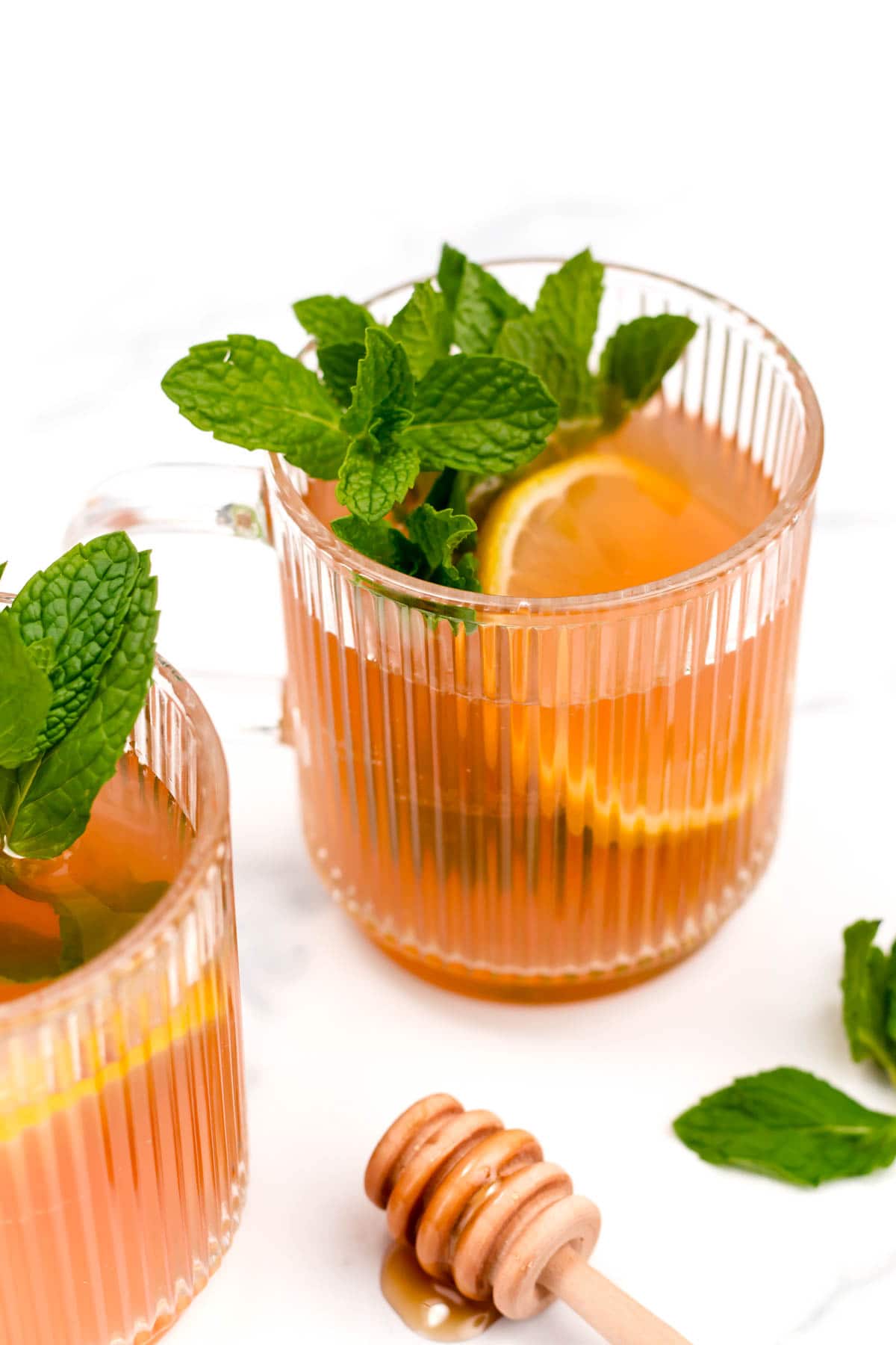 Honey citrus mint tea in a glass mug on a marble countertop. 